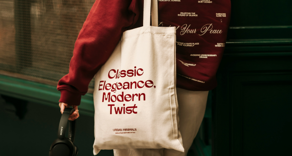 Person holding headphones whilst carrying a cotton tote bag on their shoulders